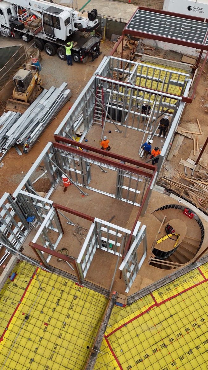 Aerial of a rebuild going up in light-gauge and structural steel, crew on site
